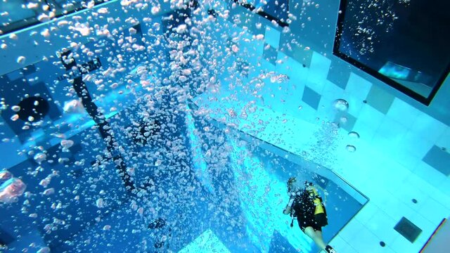 divers swim in a deep blue water training pool