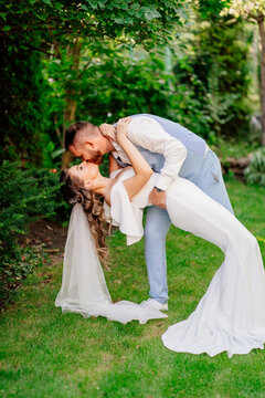 groom bent over bride in dance in park. wedding photo shoot in garden.