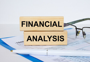 Obraz premium Wooden blocks with text Financial Analysis written on it, pen, eyeglasses