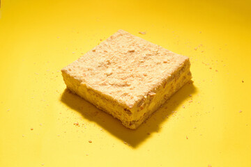 Napoleon cake on a yellow background. Shot from the side. Place for the logo