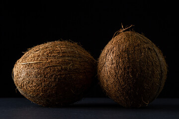 Isolated coconut on a black background. Two whole coconuts on a dark background. Healthy fruit