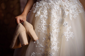 The bride holds the shoes in her hand with the heels back