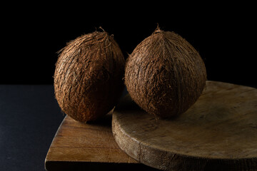 Isolated coconut on a black background. Two whole coconuts on a dark background. Healthy fruit