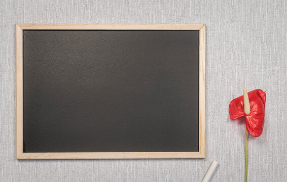 Modèle de tableau noir en ardoise avec espace vide pour logos, inscription publicitaire. Cadre en mode paysage sur un espace de travail avec une fleur.	