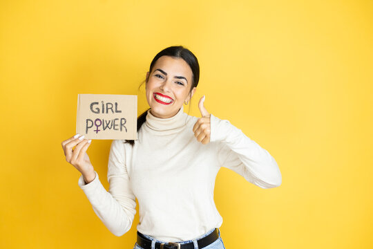 Young beautiful activist woman protesting holding poster with girl power message success sign doing positive gesture with hand, thumb up smiling and happy. cheerful expression