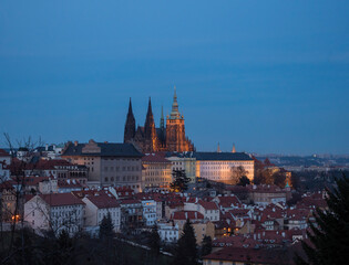 Fototapeta na wymiar Evening view of illuminated St. Vitus Cathedral gothic churche and Prague Castle panorama, hradcany and Mala Strana quarter from Petrin hill, blue sky background