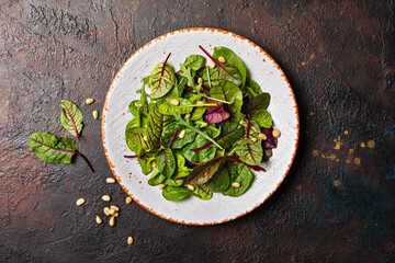 A plate with mix of fresh green leaves for salad and pine nuts