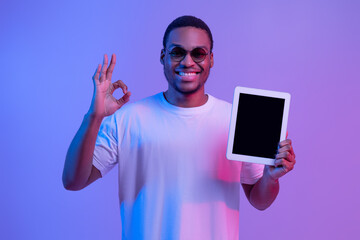 Happy African Guy In Neon Lighting Holding Digital Tablet With Black Screen