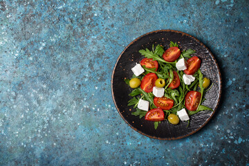 Healthy vegetarian salad with fresh arugula, cherry tomatoes, soft cheese and olives