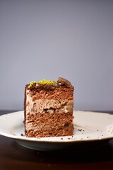 A slice of chestnut and cream cocoa cake. There are pistachios on it.