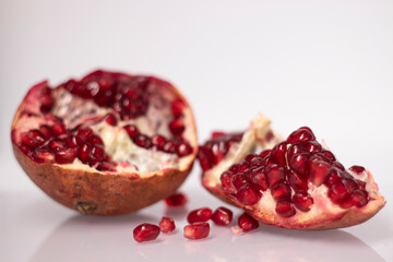Fresh ripe sliced pomegranate fruit with red seeds isolated on white background