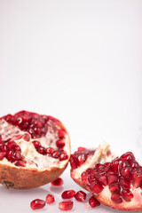 Fresh ripe sliced pomegranate fruit with red seeds isolated on white background