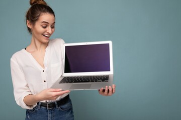 Close-up portrait of overjoyed Beautiful smiling happy young woman holding computer laptop looking at netbook having fun wearing casual smart clothes isolated over wall background