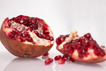 Fresh ripe sliced pomegranate fruit with red seeds isolated on white background