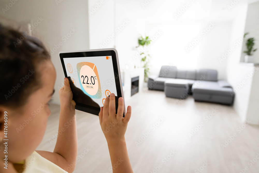 Poster shot of little girl using a domotic system with her digital tablet while standing at home.