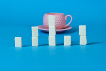 pink coffee cup and sugar on the table.blue  background.