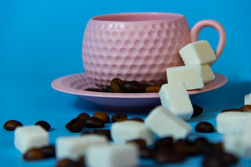 It's coffee time. pink coffee cup,sugar and coffee beans on the table.blue  background.