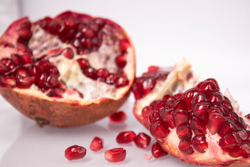 ripe fresh sliced pomegranate fruit with red seeds isolated on white background