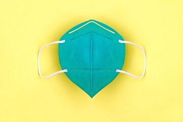 Green FFP2 n95 protective face mask on yellow background. Protection and prevention against...