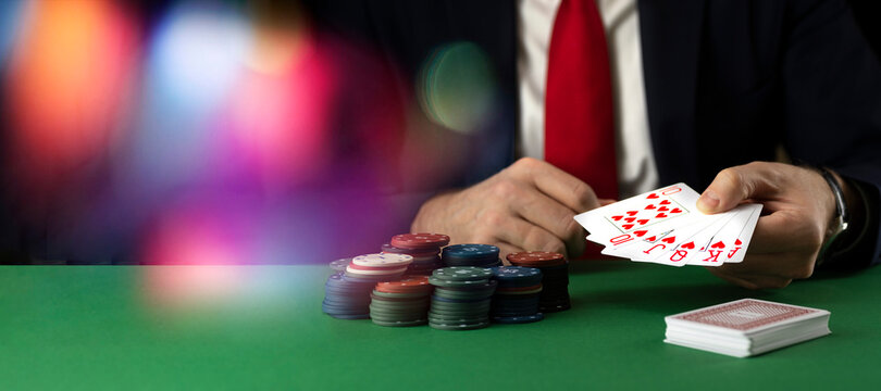 Businessman at green playing table with gambling chips and cards playing poker and blackjack in casino