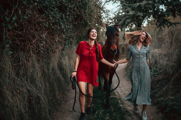 Two women friends chatting and taking a ride with their horse through the countryside