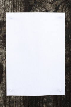 White sheet of paper on a dark wooden background for inserting text or image