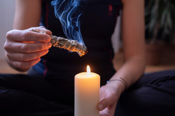 Woman's hand burning white sage in home.