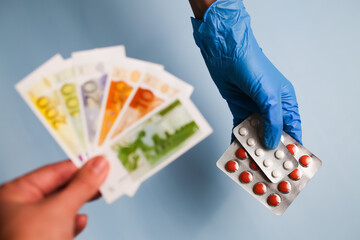 Closeup medicines in hand. Various European banknotes - Euro. The high cost of medical care and health insurance. Huge profits in the pharmaceutical industry.