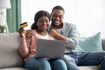Happy african american couple with credit card and laptop