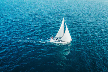 Regatta sailing ship yachts with white sails at opened sea. Aerial view of sailboat in windy condition.