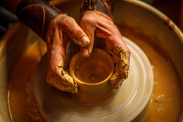 The master forms a clay cup on a potter's wheel. A potter's hands preparing a clay pot. Close-up.
