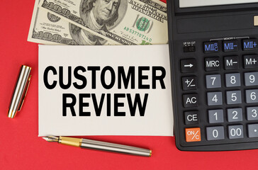 On a red background, among the money, a calculator and a pen lies a sign with the text - CUSTOMER REVIEW