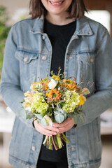 Smiling woman with orange yellow flower bouquet