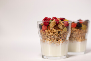 muesli dessert with yogurt and candied or dried fruits with raspberries on top in glass isolated on white background. Granola breakfast
