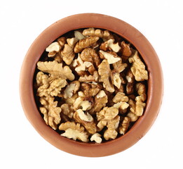 Walnut kernels, pile in clay pot isolated on white background, top view