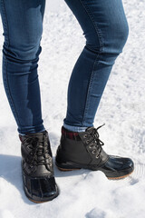 woman standing in the snow with black boots on