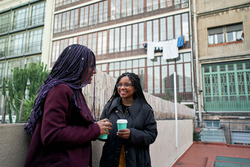 Two businesswomen have coffee after work and talk about new projects during a break in their office.