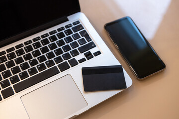 Laptop, mobile phone, credit card on the desktop. Top view, soft selective focus. Online shopping concept, e-commerce, self-isolation, banking, financial transactions, business, using technology