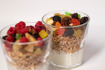 muesli dessert with yogurt and candied or dried fruits with raspberries on top in glass isolated on white background. Granola breakfast