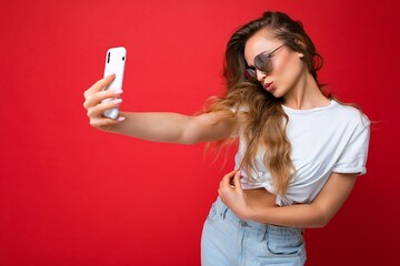 Closeup photo of amazing beautiful young blonde woman holding mobile phone taking selfie photo...