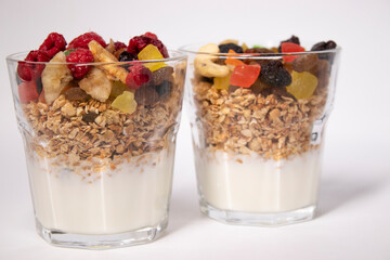 muesli dessert with yogurt and candied or dried fruits with raspberries on top in glass isolated on white background. Granola breakfast