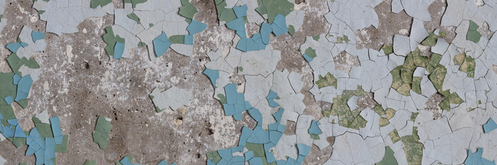 Peeling paint on the wall. Panorama of a concrete wall with old cracked flaking paint. Weathered rough painted surface with patterns of cracks and peeling. Wide panoramic grungy texture for background