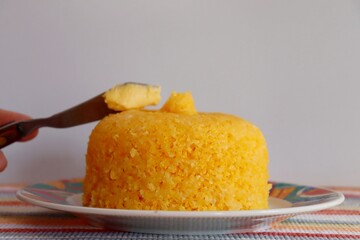 Woman's hand putting butter on couscous. Brazilian couscous (Cuscuz Brasileiro).