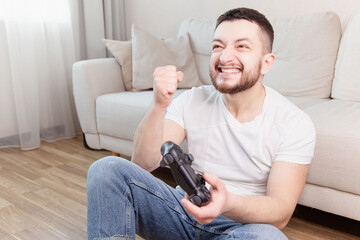 Happy young man playing and winning online game on computer.Competitive gaming, electronic sports, technology, gaming, entertainment concept. Life at home.