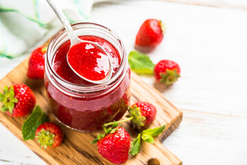 Strawberry jam in the glass jar with fresh berries. Close up.