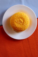 Brazilian Couscous (Cuscuz Brasileiro) on blue and orange background. Typical Northeast Brazilian dish. Vertical photo.
