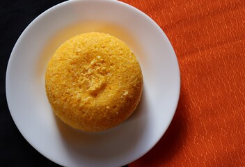 Brazilian Couscous on orange background, with place for text. Corn couscous. Brazilian food. 