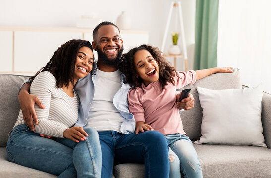 Happy young family watching television sitting on sofa