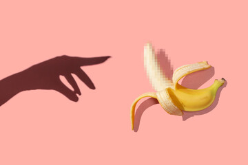 Symbol of the penis in the form of a ripe banana with blurred censored squares and female hand on a pink background, place for text. Sex concept of man's potency and erection. © Northern life