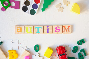 watercolor paints and children's educational toys on a light background, the inscription autism on wooden squares